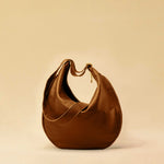 The Saddle Bag IVY by LABEL17 is crafted from supple, vegetable-tanned nappa leather and defined by its distinctive hand-stitched side seams. Its softly curved saddle silhouette rests comfortably against the body. The bag features a zip closure, a leather-lined interior, and a secure inner pocket. The adjustable strap allows it to be worn over the shoulder or crossbody – a versatile piece for everyday use. Handmade in Morocco.