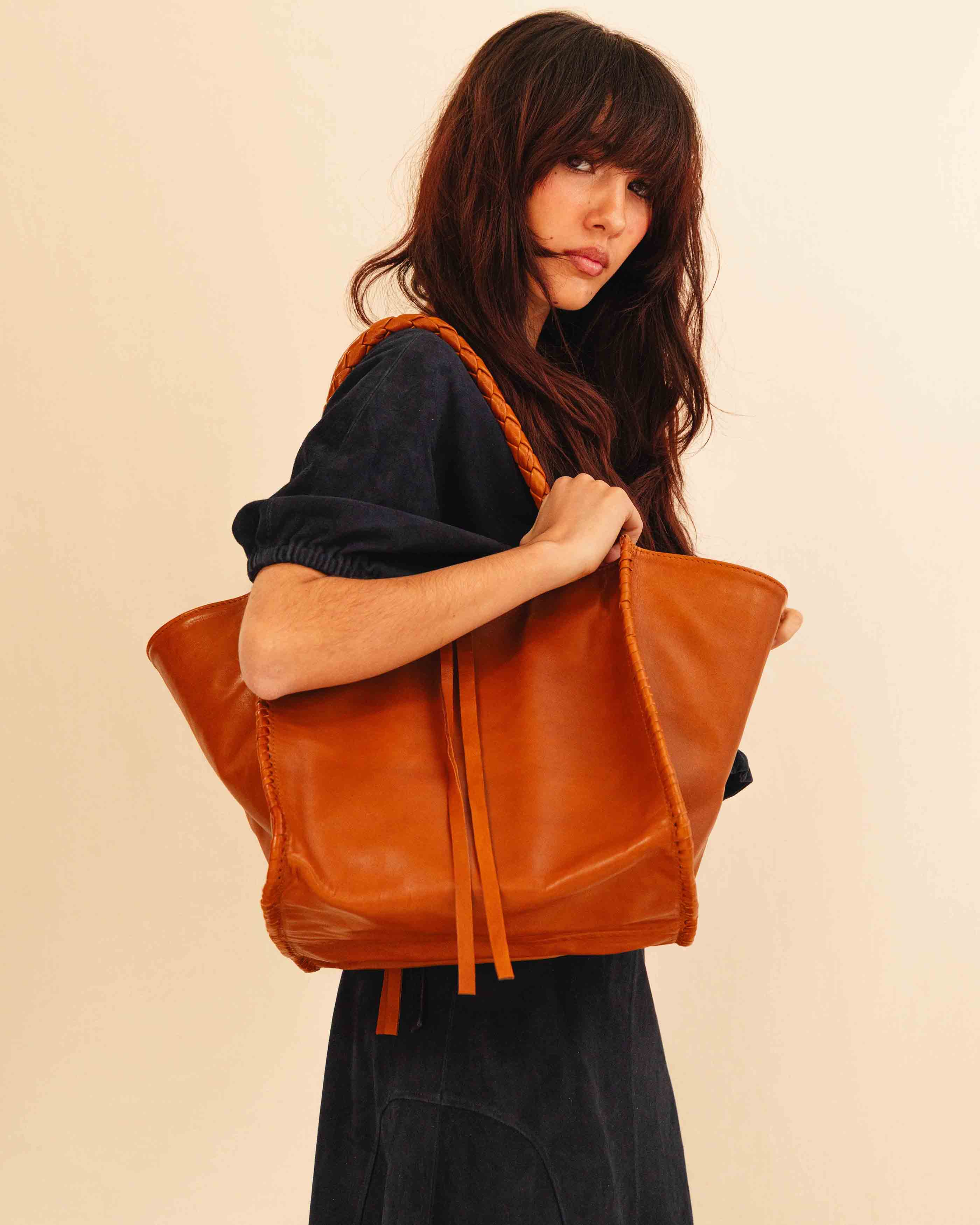 Die Shoulder Bag IVY von LABEL17 ist aus geschmeidigem Nappaleder gefertigt und zeichnet sich durch handwerkliche Details wie markante Seitennähte und lange, geflochtene Henkel aus. Mit den Lederbändern lässt sich die Tasche elegant zuschnüren – eine gelungene Verbindung von Funktion und Raffinesse.