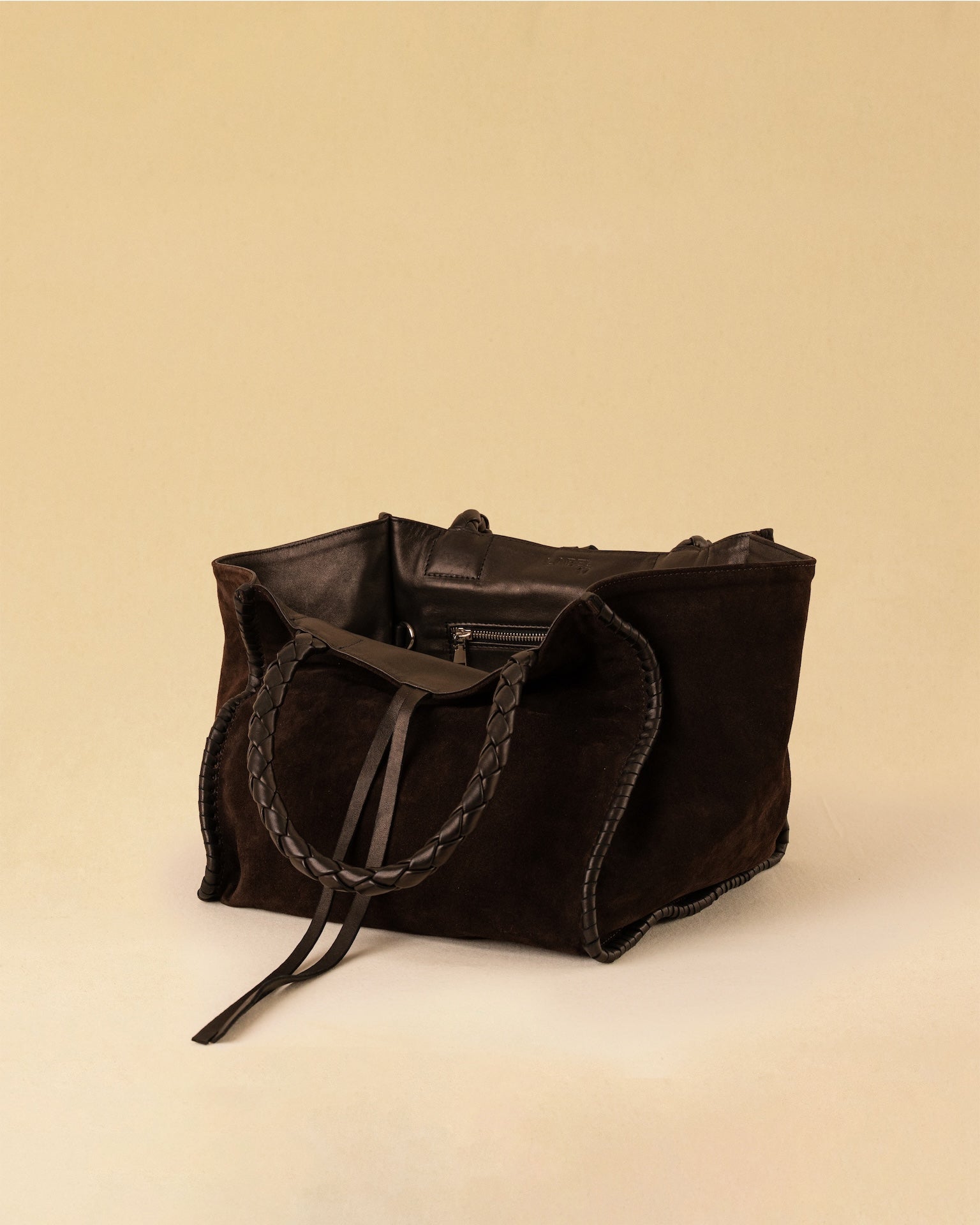Die Shoulder Bag IVY von LABEL17 ist aus geschmeidigem Velours-Leder gefertigt und zeichnet sich durch handwerkliche Details wie markante Seitennähte und lange, geflochtene Henkel aus. Mit den Lederbändern lässt sich die Tasche elegant zuschnüren – eine gelungene Verbindung von Funktion und Raffinesse.