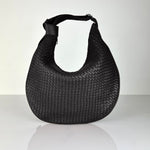 The LABEL17 Shoulder Bag Saddle Tresse is braided by hand and crafted from the most supple Nappa leather exemplifying luxury and durability. Designed with a unique saddle shape, it conforms seamlessly to your body. The bag is lined with leather and has practical compartments, including a zippered compartment for safe storage. Featuring a zipper and an adjustable shoulder strap, this versatile accessory offers the freedom to be worn over the shoulder or across the body.