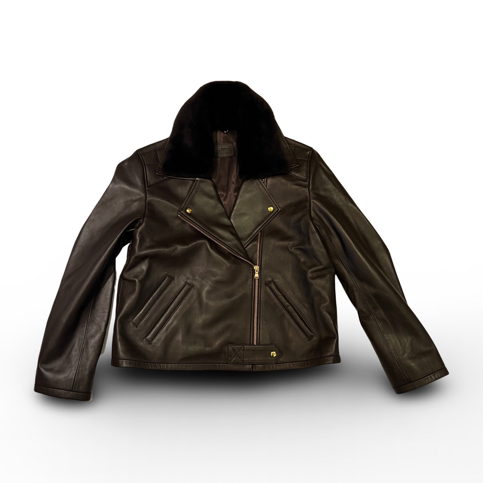 Die dunkelbraune Lederjacke KATE von LABEL17, eine klassische Perfecto, überzeugt durch stilvolle Details wie den abnehmbaren Lammfell-Kragen-Besatz. Gefertigt aus feinstem Nappaleder, ist diese Jacke ein zeitloses Highlight. Die goldenen Beschläge verleihen dem Design einen lässigen, und gleichzeitig eleganten Touch. Diese Jacke von höchster Qualität ist eine gute Investition und wird Sie jahrelang begleiten.