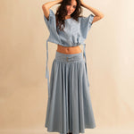 Der Skirt CRISTY von LABEL17 in einem klassischen Blau-Weiss Vichy-Karo-Muster fällt in einer weiten Maxi-Länge und verleiht jedem Look eine feminine Leichtigkeit. Zwei Zierschnallen im Bund setzen einen eleganten Akzent. Reissverschluss vorne und elastischer Bund hinten sorgen für angenehmen Tragekomfort.
