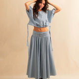 Der Skirt CRISTY von LABEL17 in einem klassischen Blau-Weiss Vichy-Karo-Muster fällt in einer weiten Maxi-Länge und verleiht jedem Look eine feminine Leichtigkeit. Zwei Zierschnallen im Bund setzen einen eleganten Akzent. Reissverschluss vorne und elastischer Bund hinten sorgen für angenehmen Tragekomfort.