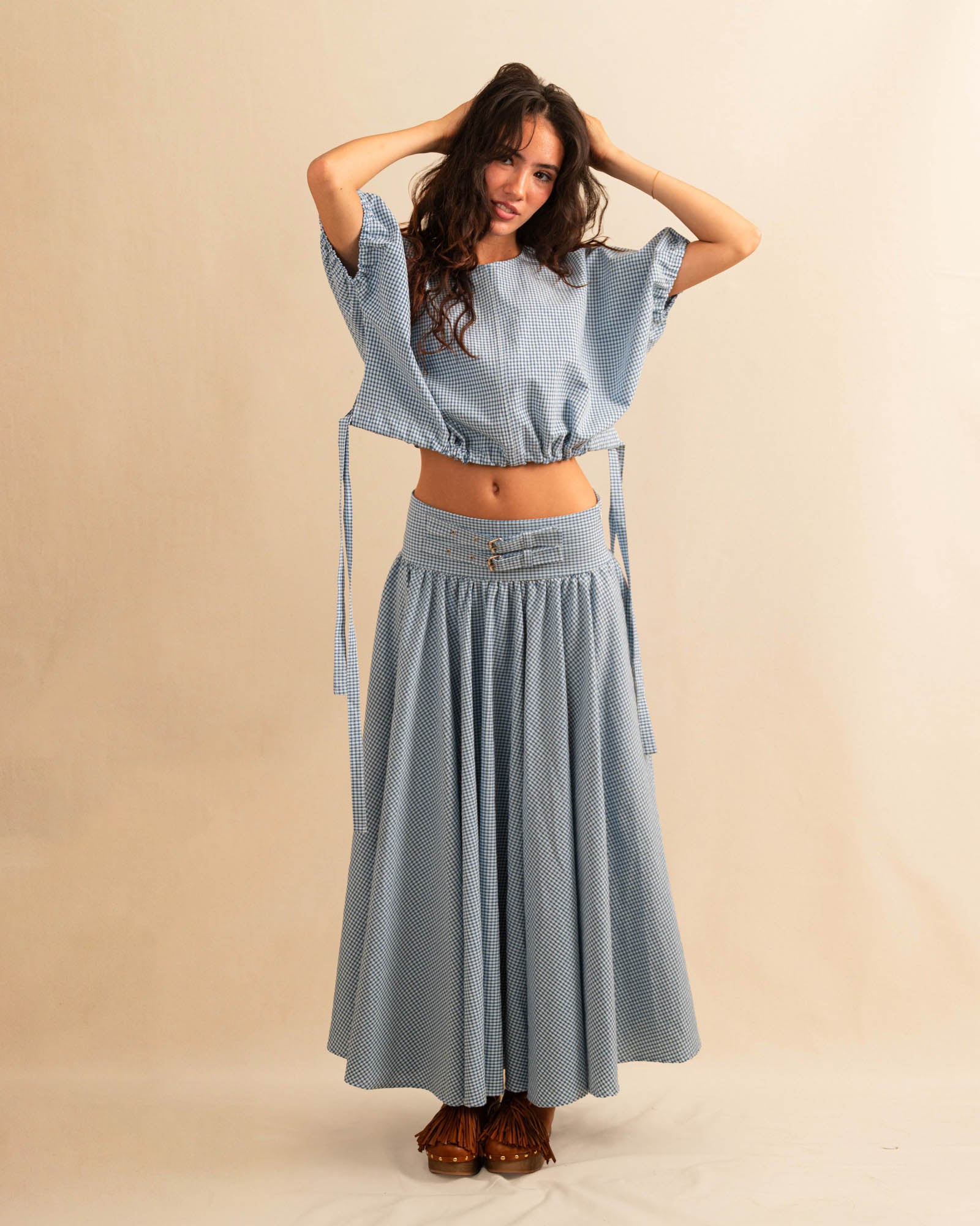 Der Skirt CRISTY von LABEL17 in einem klassischen Blau-Weiss Vichy-Karo-Muster fällt in einer weiten Maxi-Länge und verleiht jedem Look eine feminine Leichtigkeit. Zwei Zierschnallen im Bund setzen einen eleganten Akzent. Reissverschluss vorne und elastischer Bund hinten sorgen für angenehmen Tragekomfort.