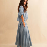 Der Skirt CRISTY von LABEL17 in einem klassischen Blau-Weiss Vichy-Karo-Muster fällt in einer weiten Maxi-Länge und verleiht jedem Look eine feminine Leichtigkeit. Zwei Zierschnallen im Bund setzen einen eleganten Akzent. Reissverschluss vorne und elastischer Bund hinten sorgen für angenehmen Tragekomfort.