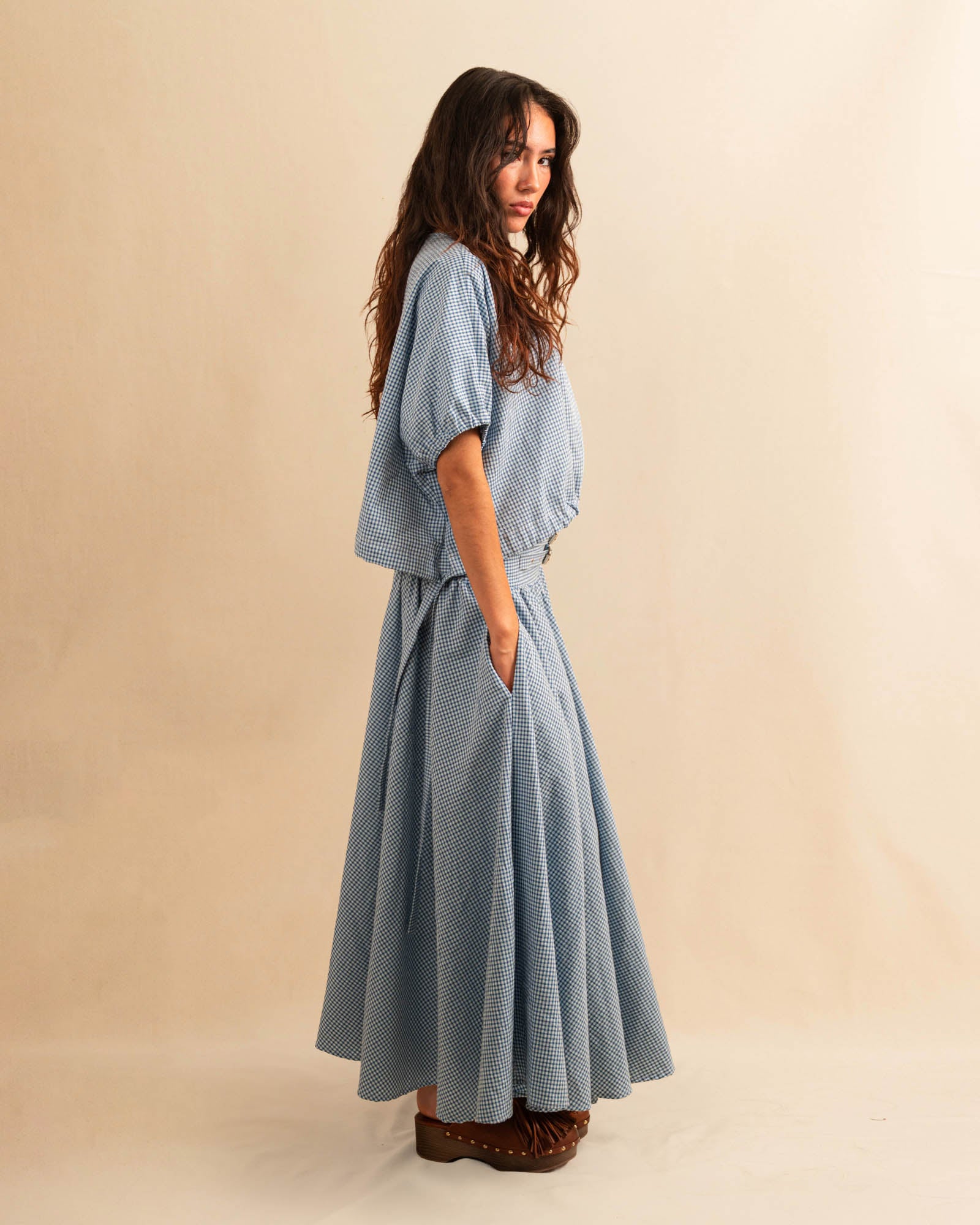 Der Skirt CRISTY von LABEL17 in einem klassischen Blau-Weiss Vichy-Karo-Muster fällt in einer weiten Maxi-Länge und verleiht jedem Look eine feminine Leichtigkeit. Zwei Zierschnallen im Bund setzen einen eleganten Akzent. Reissverschluss vorne und elastischer Bund hinten sorgen für angenehmen Tragekomfort.