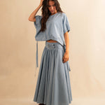 Der Skirt CRISTY von LABEL17 in einem klassischen Blau-Weiss Vichy-Karo-Muster fällt in einer weiten Maxi-Länge und verleiht jedem Look eine feminine Leichtigkeit. Zwei Zierschnallen im Bund setzen einen eleganten Akzent. Reissverschluss vorne und elastischer Bund hinten sorgen für angenehmen Tragekomfort.