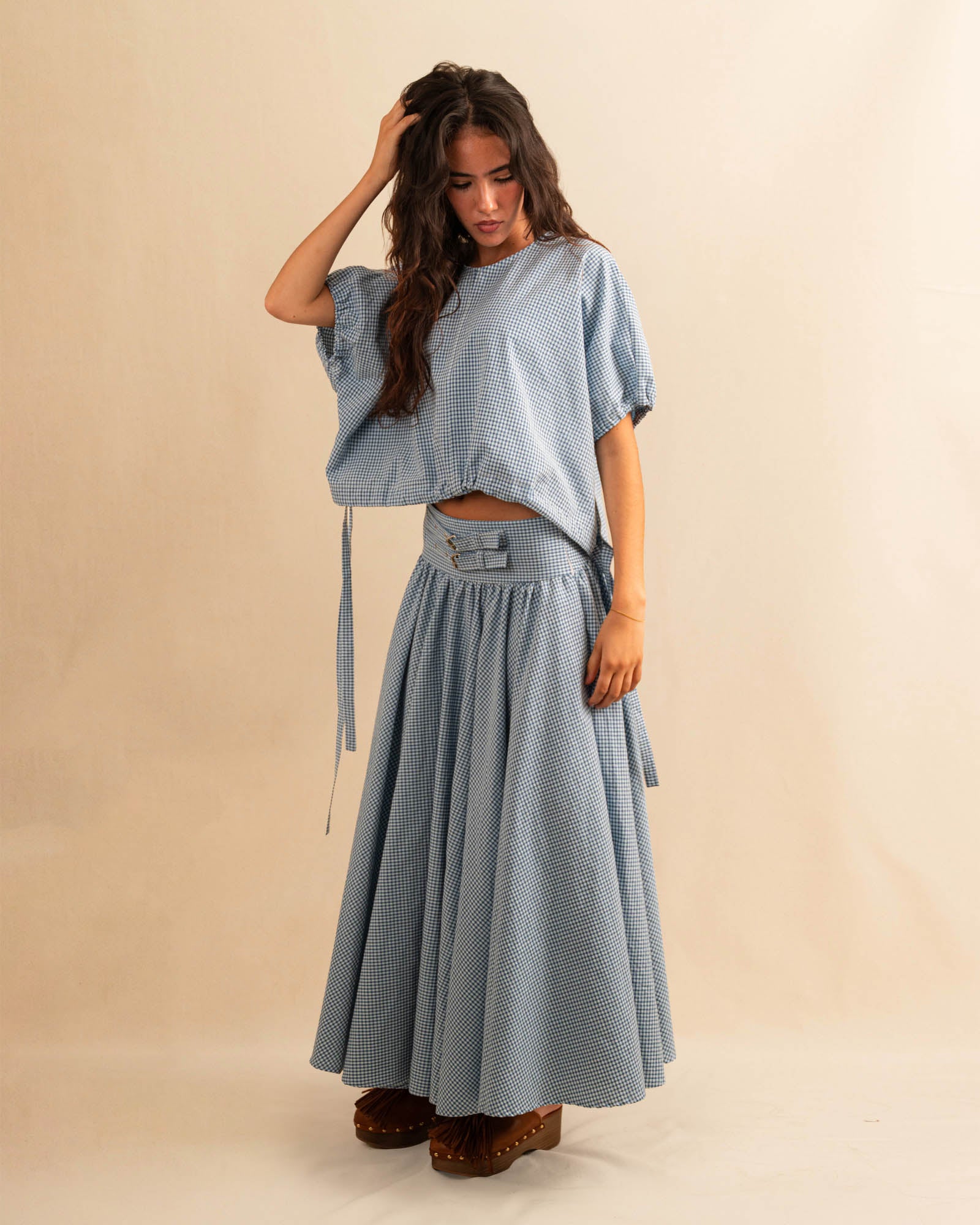 Der Skirt CRISTY von LABEL17 in einem klassischen Blau-Weiss Vichy-Karo-Muster fällt in einer weiten Maxi-Länge und verleiht jedem Look eine feminine Leichtigkeit. Zwei Zierschnallen im Bund setzen einen eleganten Akzent. Reissverschluss vorne und elastischer Bund hinten sorgen für angenehmen Tragekomfort.