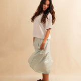 LABEL17's Skirt LINA ist ein Faltenrock aus Baumwolle, veredelt mit einem handgenähten Zierstich (Hbik-Stitch) an der linken und rechten Seite. Falten auf der Vorderseite und ein elastischer Einsatz am Rücken sorgen für angenehmen Tragekomfort. Perfekt für den Sommer.