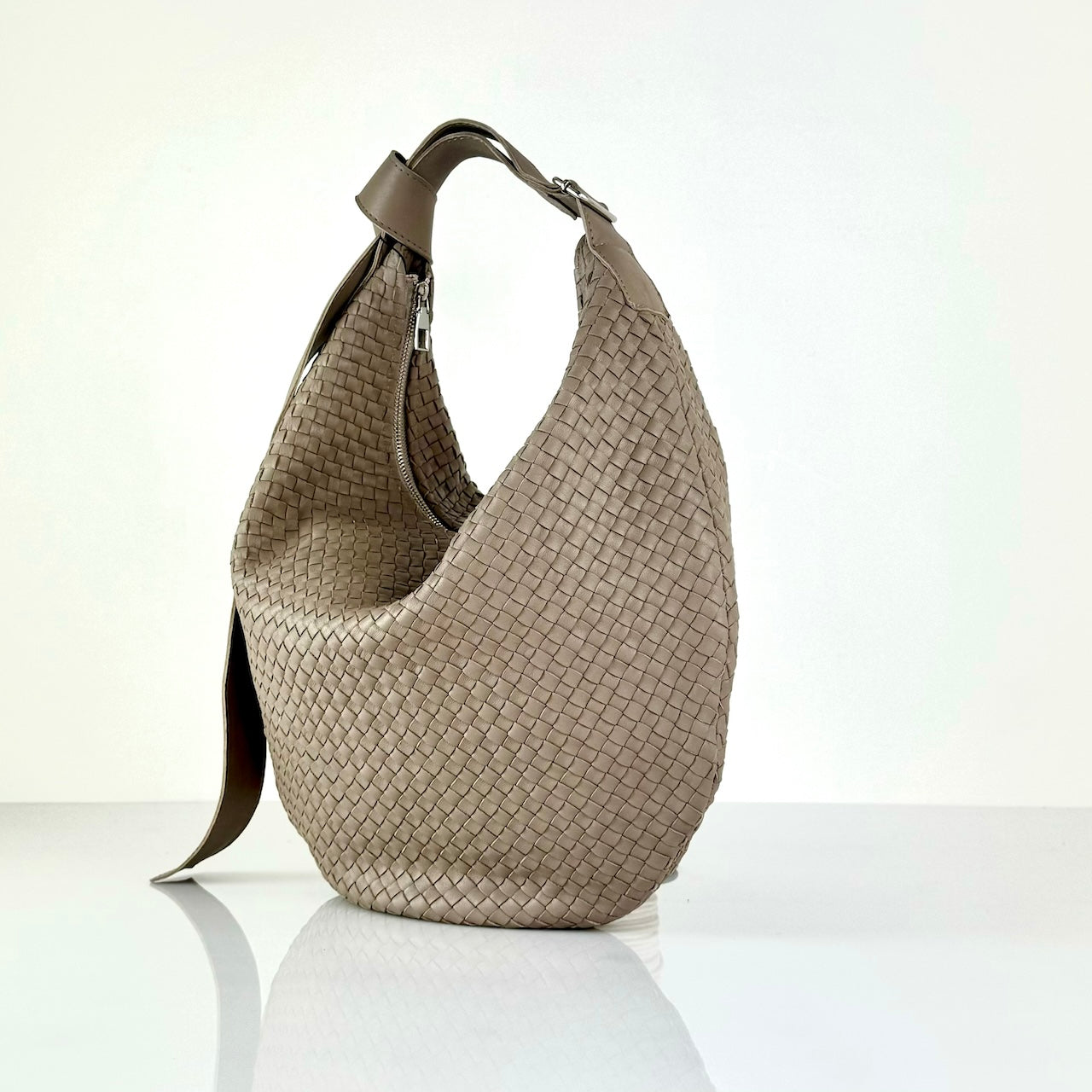 The LABEL17 Shoulder Bag Saddle Tresse is braided by hand and crafted from the most supple Nappa leather exemplifying luxury and durability. Designed with a unique saddle shape, it conforms seamlessly to your body. The bag is lined with leather and has practical compartments, including a zippered compartment for safe storage. Featuring a zipper and an adjustable shoulder strap, this versatile accessory offers the freedom to be worn over the shoulder or across the body.