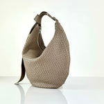 The LABEL17 Shoulder Bag Saddle Tresse is braided by hand and crafted from the most supple Nappa leather exemplifying luxury and durability. Designed with a unique saddle shape, it conforms seamlessly to your body. The bag is lined with leather and has practical compartments, including a zippered compartment for safe storage. Featuring a zipper and an adjustable shoulder strap, this versatile accessory offers the freedom to be worn over the shoulder or across the body.