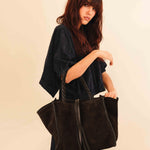 Die Shoulder Bag IVY von LABEL17 ist aus geschmeidigem Velours-Leder gefertigt und zeichnet sich durch handwerkliche Details wie markante Seitennähte und lange, geflochtene Henkel aus. Mit den Lederbändern lässt sich die Tasche elegant zuschnüren – eine gelungene Verbindung von Funktion und Raffinesse.